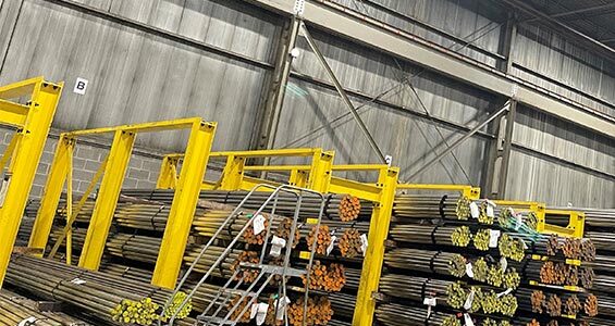 Bundled steel bars are safely stacked in yellow bar rack inside a warehouse.
